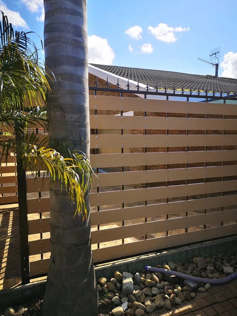 Composite slat boundary fence with decorative spike tops along residential garden in Cape Town