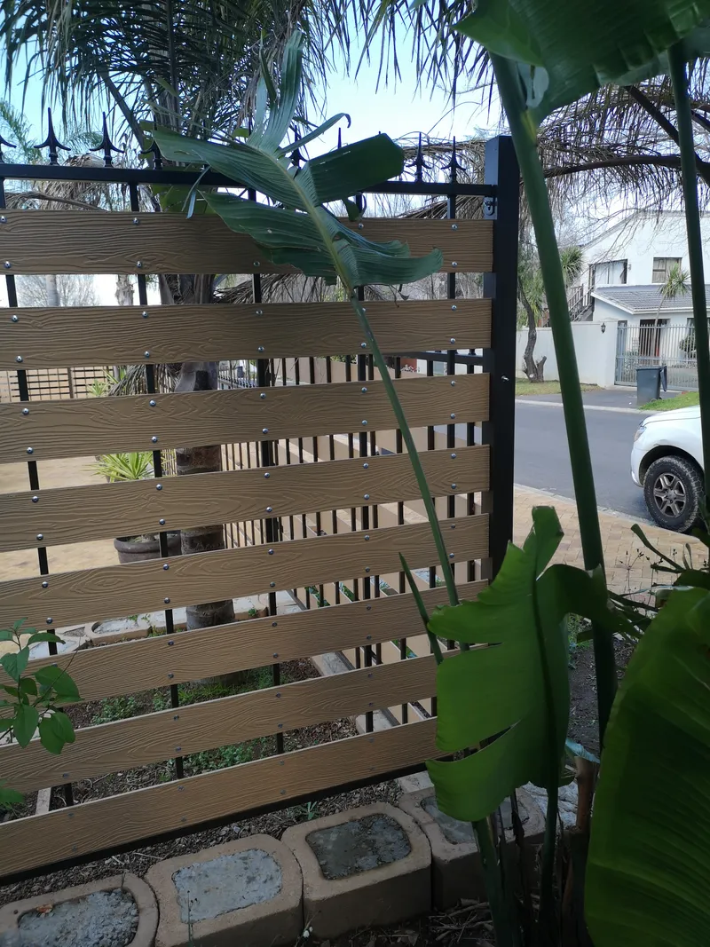 Woodgrain composite slat streetside boundary fence with decorative spike tops in Cape Town suburb