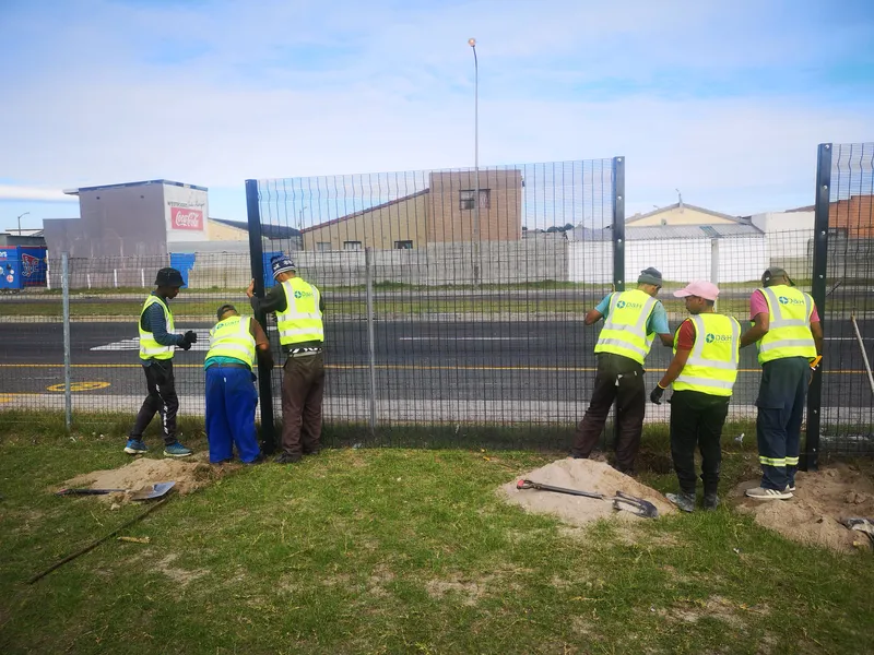 D&H Fencing crew in branded hi-vis vests installing clearview fence posts in Cape Town
