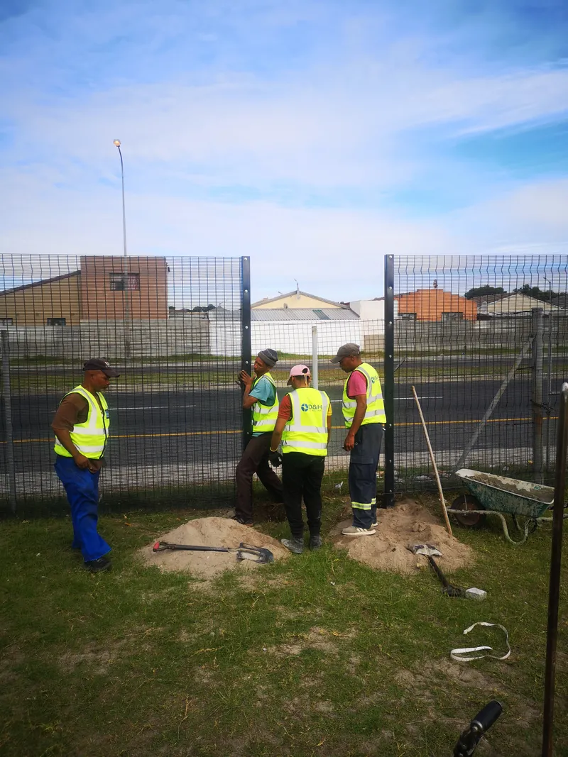 D&H Fencing crew setting clearview fence posts with wheelbarrow and tools Cape Town