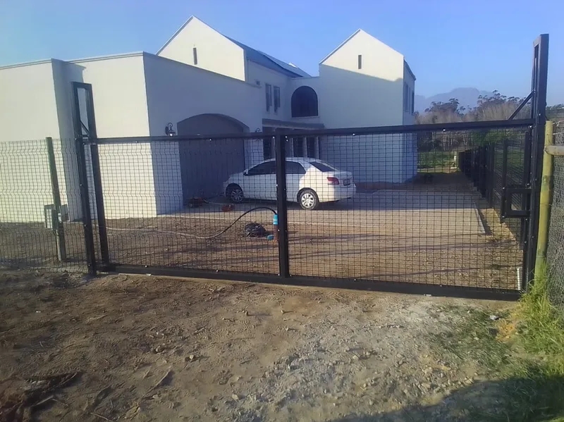 Black Clearview mesh driveway gate with pedestrian gate at modern Cape Town winelands residence