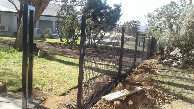 Black Clearview mesh fence and gate at smallholding property with stone wall foundation in the Western Cape