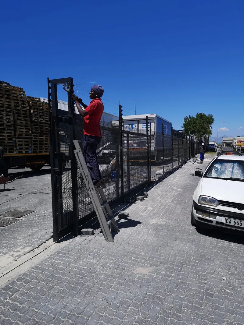 D&H Fencing installer fitting a black Clearview mesh sliding gate at a commercial logistics yard in Cape Town