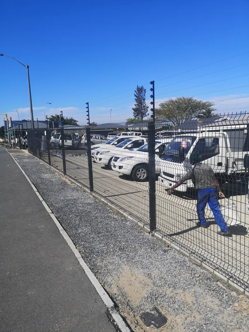 D&H Fencing technician installing clearview fence with electric top at Cape Town commercial yard