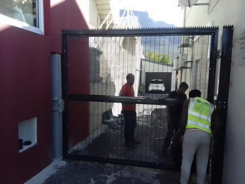 Black clearview spike-top gate installed beside red wall with Table Mountain view