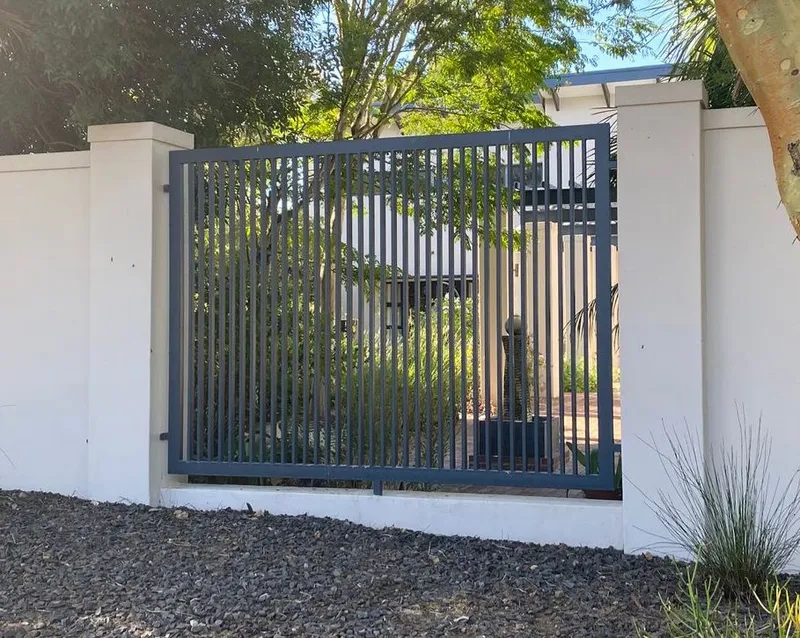 Charcoal grey tubular bar pedestrian gate set in white wall at Cape Town home