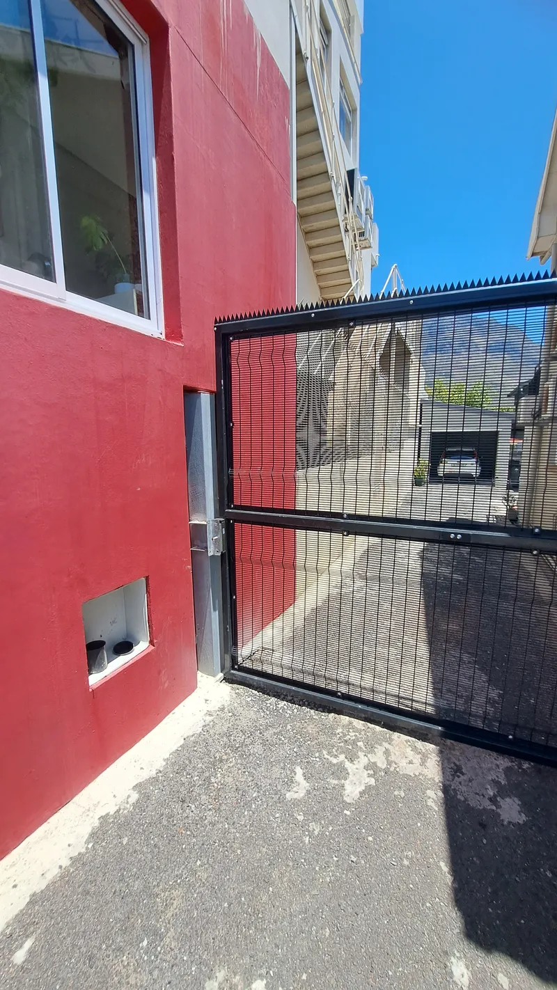 Black Clearview mesh security gate fitted against red commercial wall in Cape Town, Western Cape