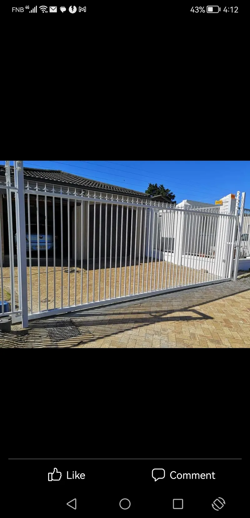White tubular bar sliding driveway gate at residential home in Cape Town with paved driveway