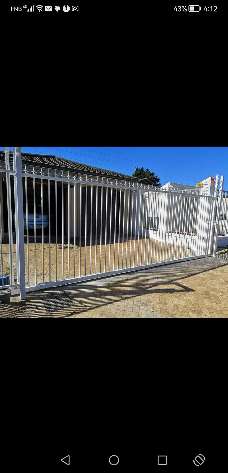 White tubular bar sliding driveway gate with spike tops at Cape Town residential home