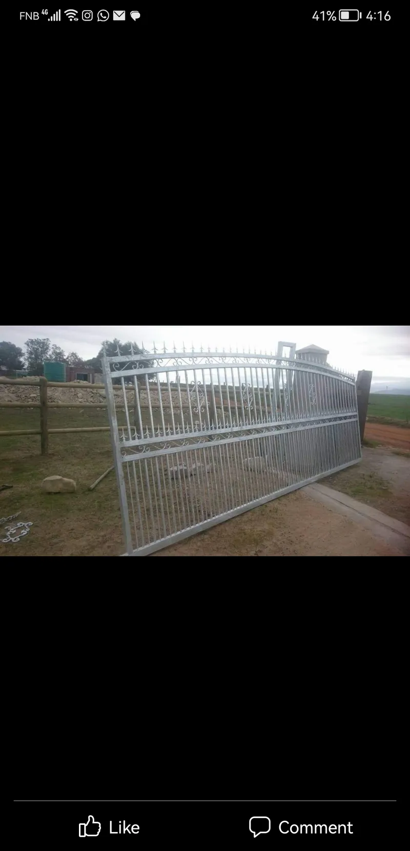 Large galvanised steel driveway gate with decorative scrollwork at farm entrance in Western Cape