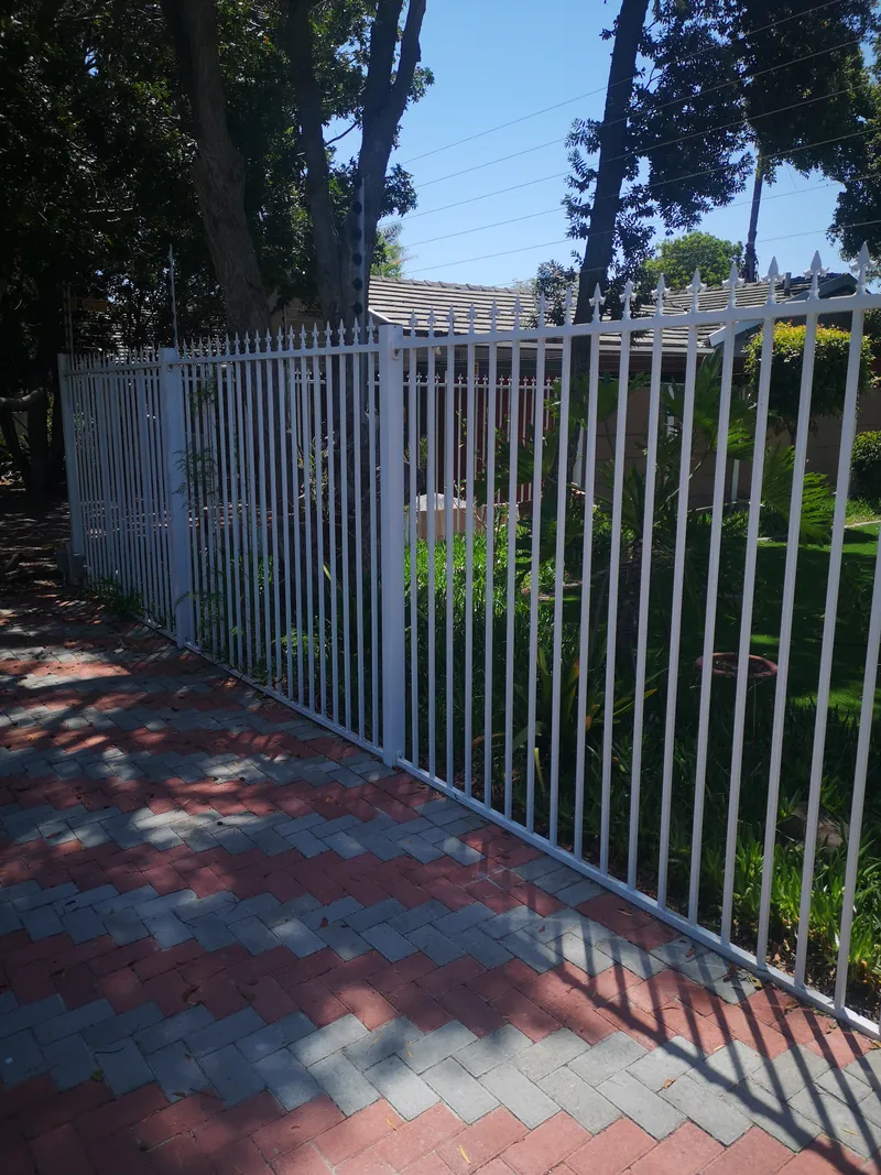 White steel tubular bar fence with electric fence top wires at Cape Town residential home