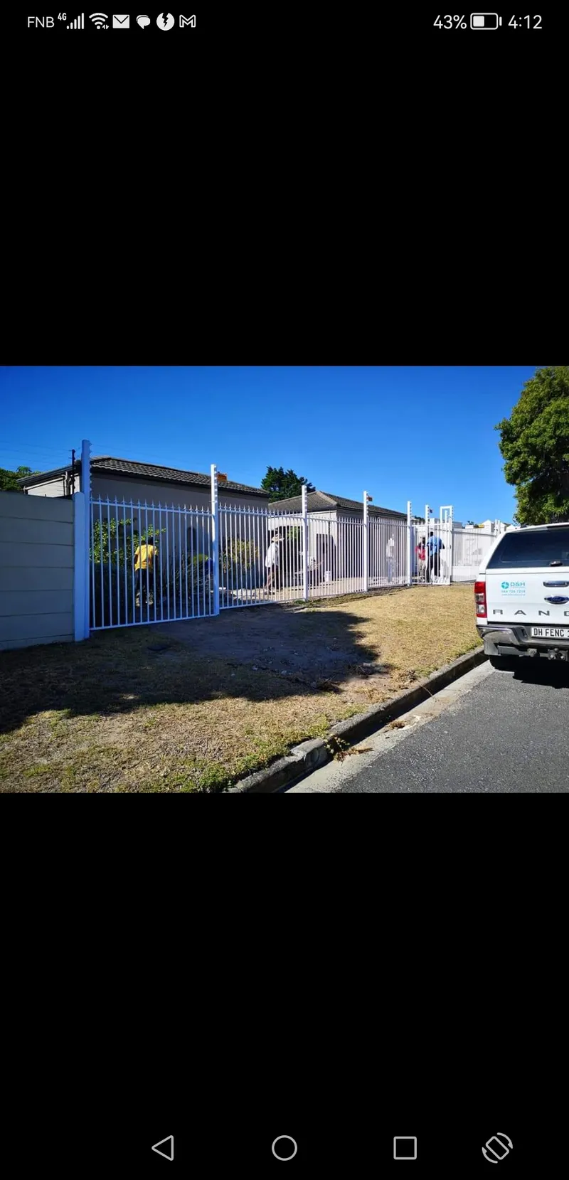 White tubular bar boundary fence with team installing at Cape Town residential property