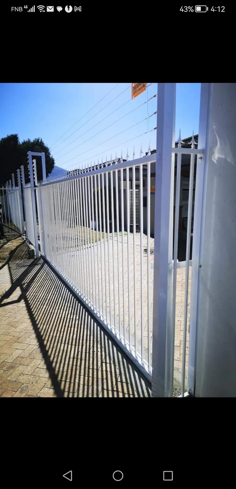 White tubular bar fence with electric top wires and spike tops on Cape Town residential boundary