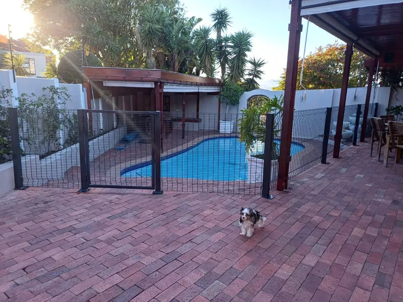 Black mesh pool safety fence enclosing residential swimming pool in Cape Town suburb