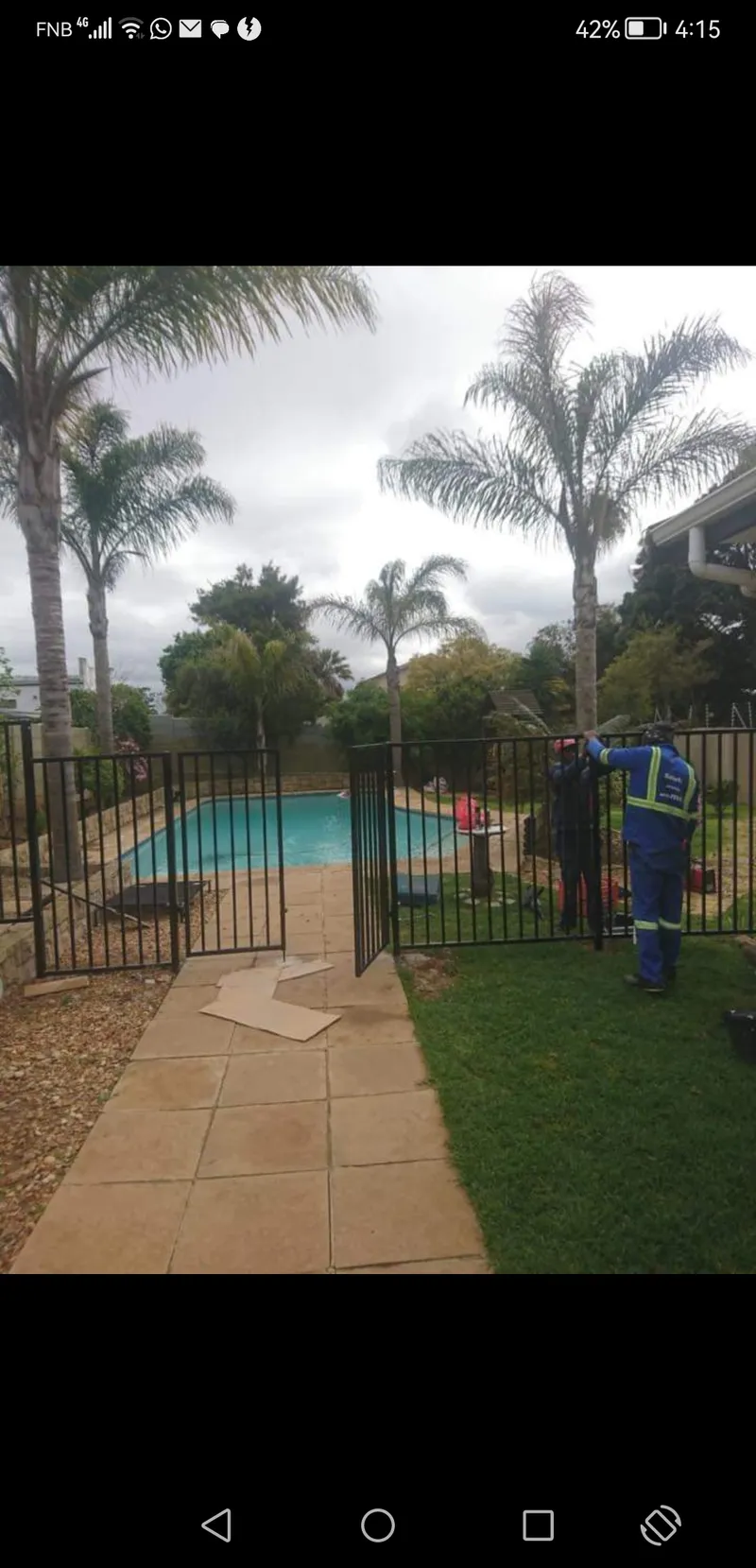 Black tubular steel pool safety fence with gate being installed in Cape Town garden