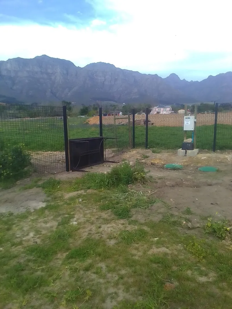 Welded mesh fence with gate frame being installed at Western Cape winelands residential plot